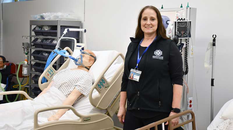 Respirtory Care instructor standing in a simulated hospital room