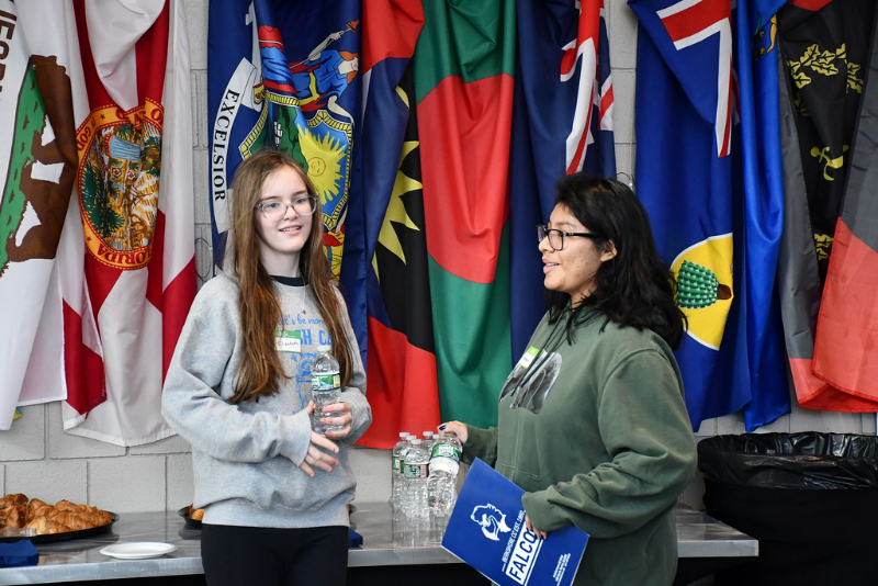 Students standing in front of the flag wall